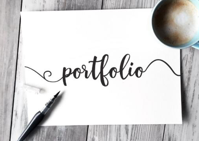 Word "Portfolio" written in cursive on paper with a pen and cup of tea next to it